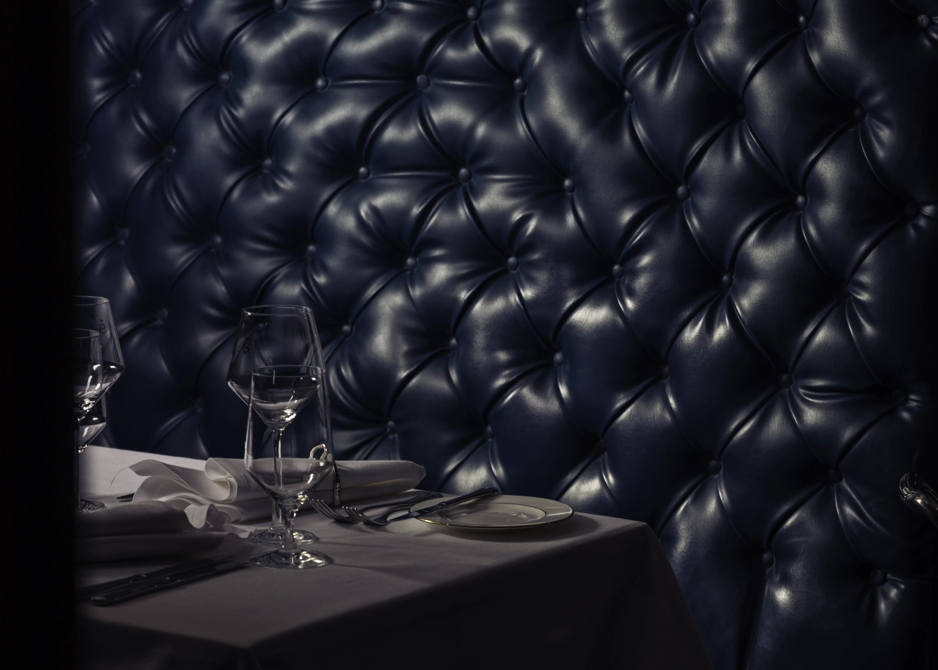 A booth in The Saddle Room at The Shelbourne, its buttoned navy leather lit from above